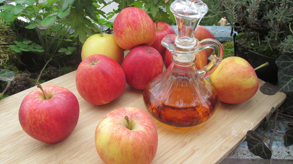 Carafe de vinaigre de pomme sur une table avec des pommes