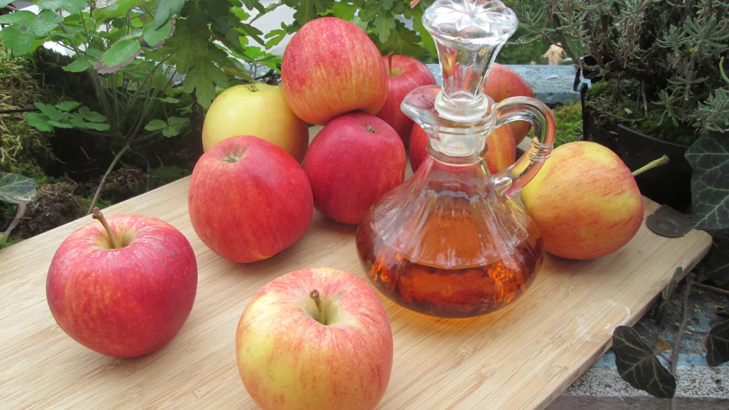 carafe of cider vinegar on the table with apples