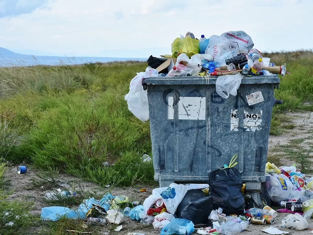 Overvolle vuilniscontainer vol wegwerp plastic en blikjes.