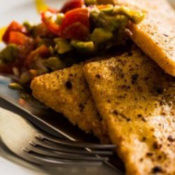 Goldbraun gebackene Panelle serviert mit einem Salat aus Avocado und Tomate