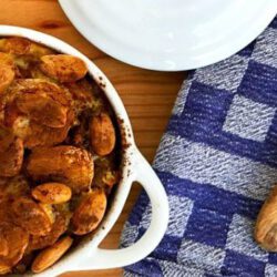 witte ovenschaal met deksel gevuld met vegetarische boboti met houten opscheplepel op keukenhanddoek